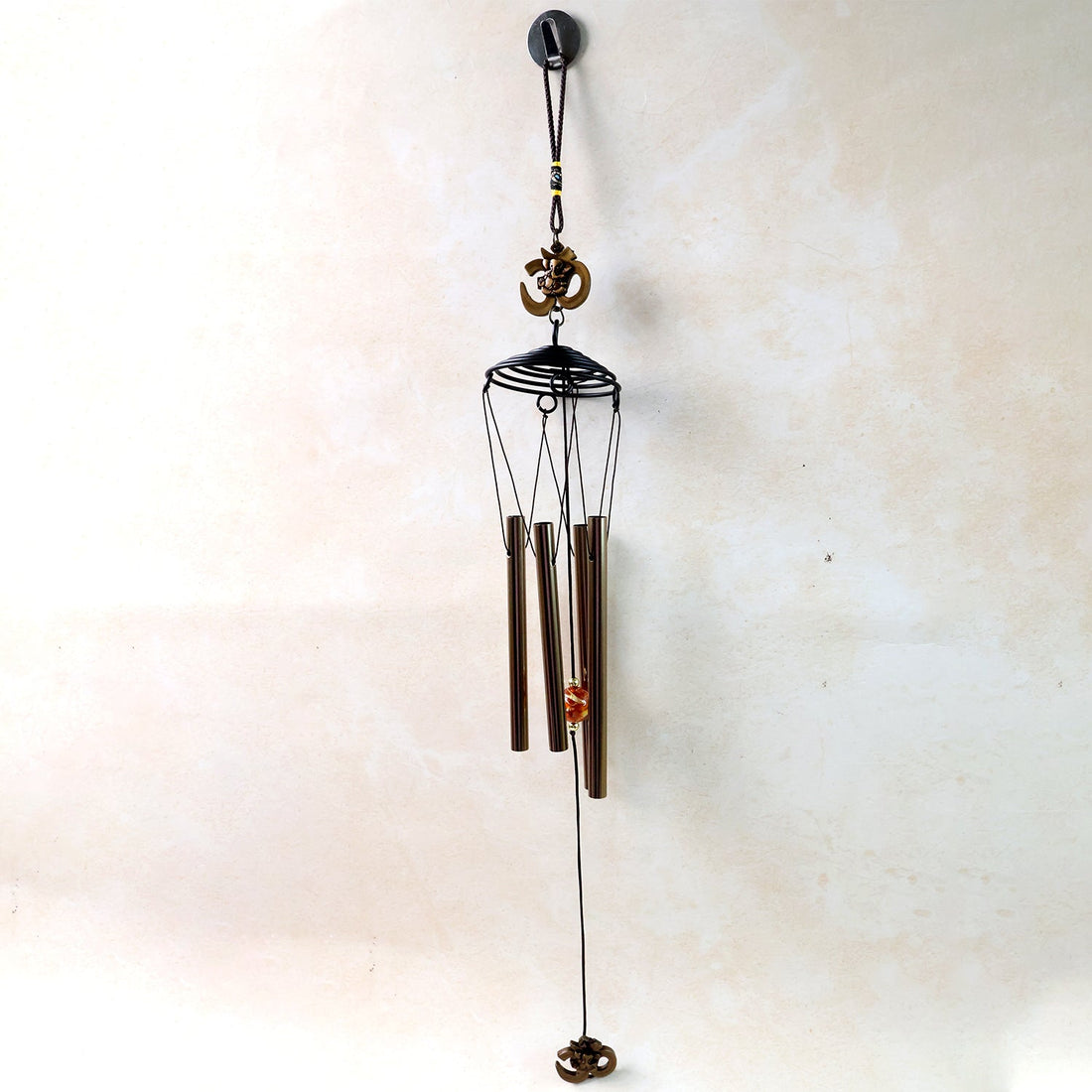 Metal Om symbol wind chime hanging on a wooden porch